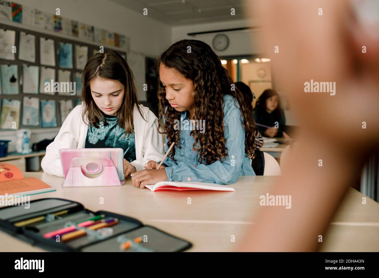 Estudiantes mujeres que usan tabletas en la mesa en el aula Foto de stock