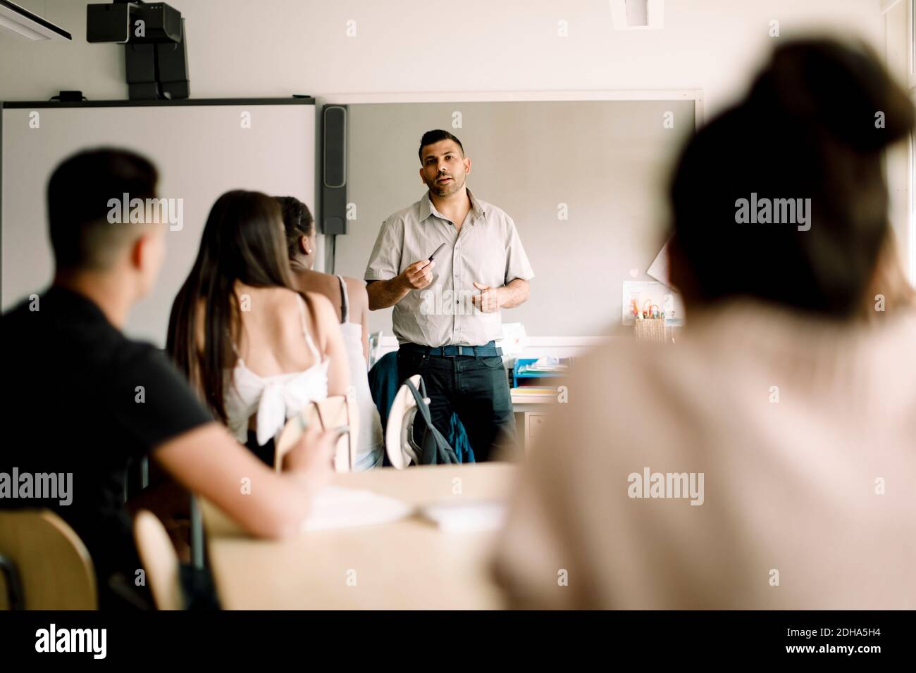 Profesor enseñando mientras los estudiantes adolescentes están sentados en el aula Foto de stock