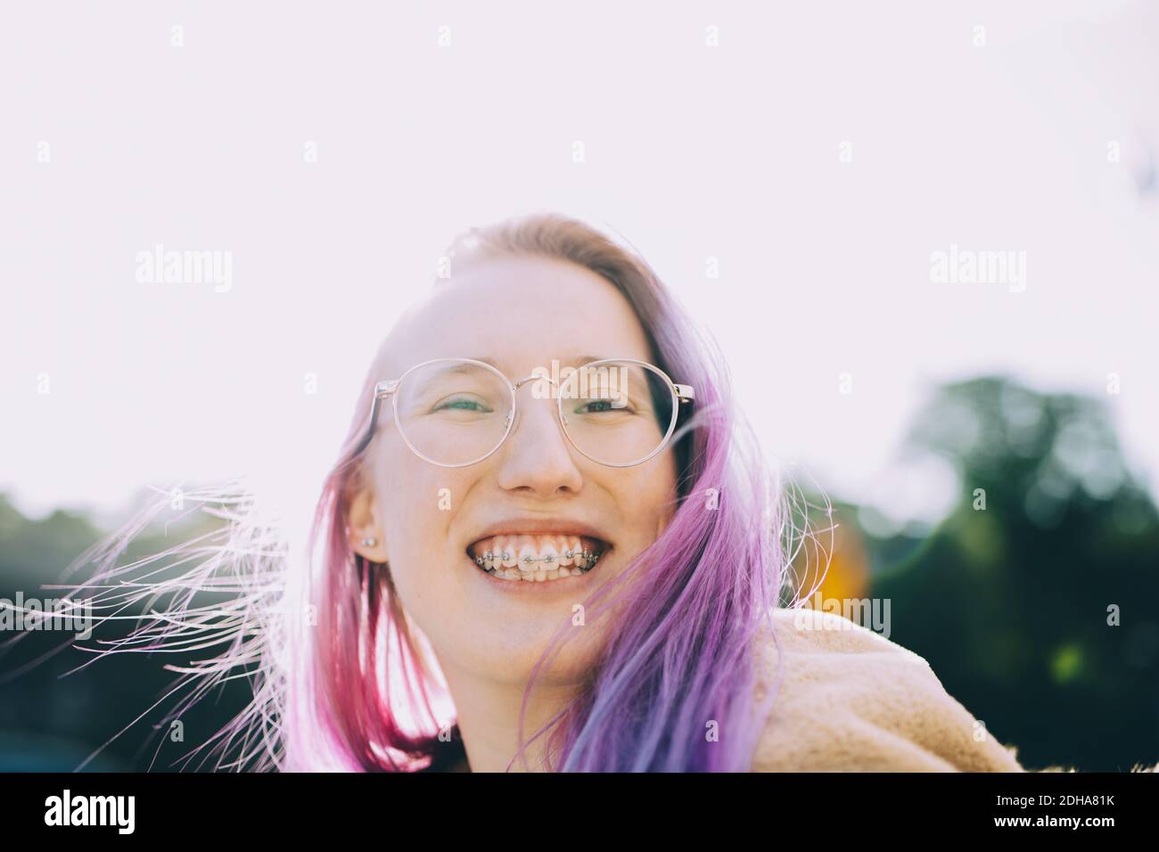 Retrato de una niña adolescente sonriente de pie contra el cielo despejado Foto de stock