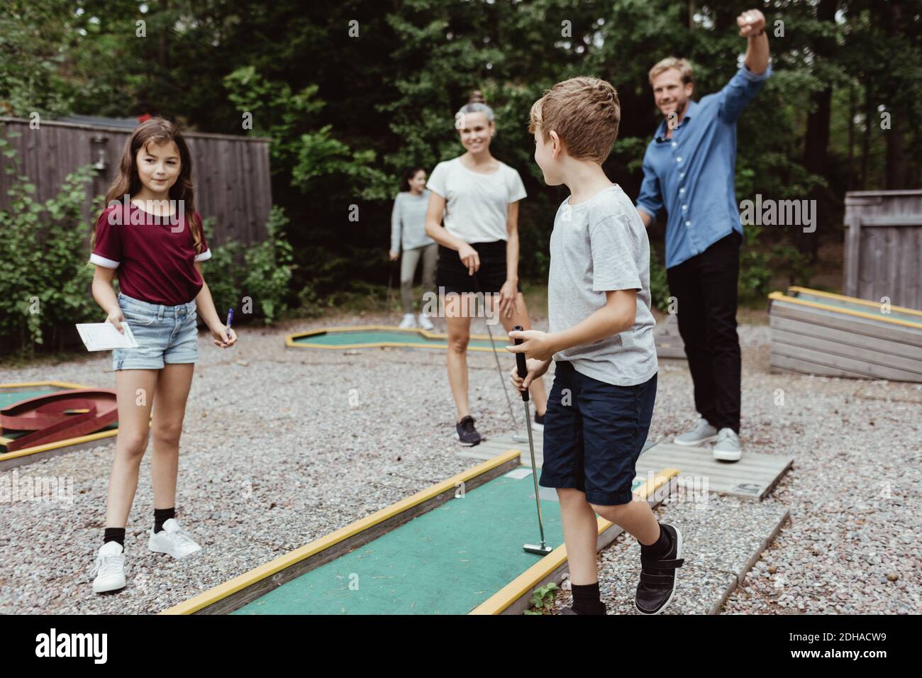 Toda la familia jugando al minigolf en el patio trasero Foto de stock