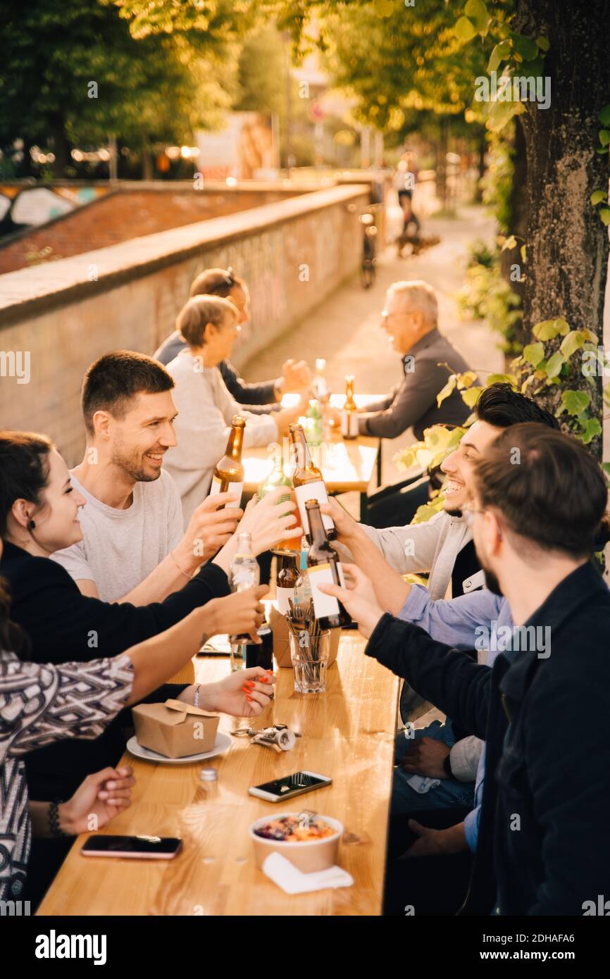Feliz hombre y mujer amigos tostar cerveza mientras se sienta jardín Foto de stock