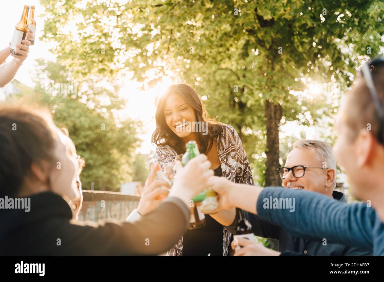 Mujer joven con bebida de pie mientras tostar en la reunión social Foto de stock