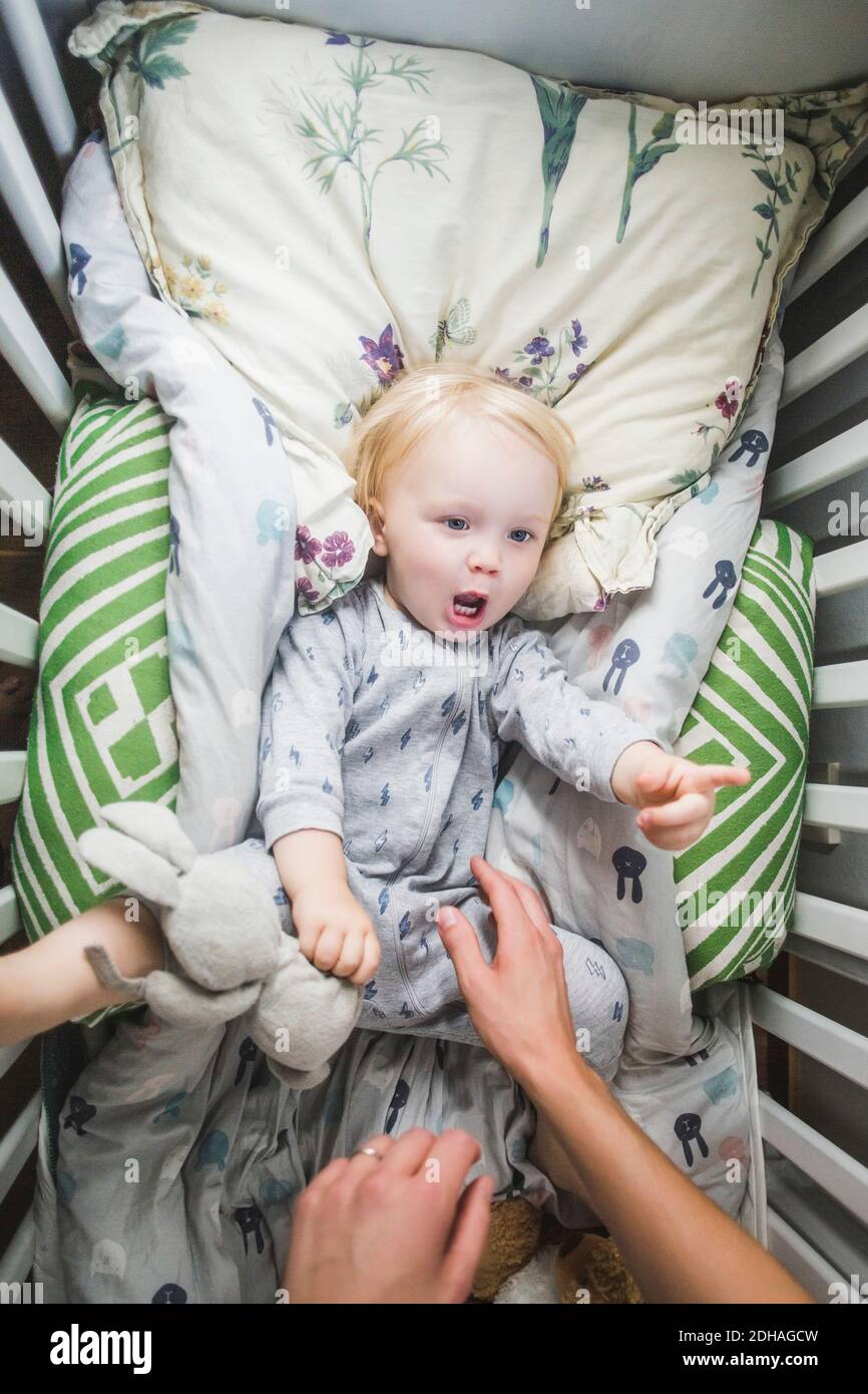 Directamente sobre la vista del niño tumbado en la cuna mientras apuntando y mirando al padre Foto de stock