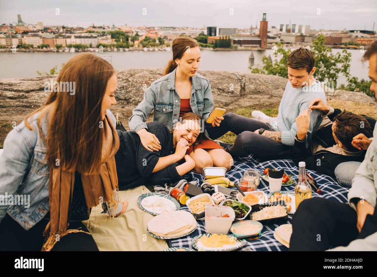 Hombres y mujeres amigos disfrutando de la comida en la manta de picnic Foto de stock