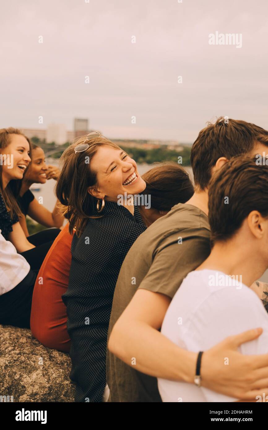 Amigos alegres divertirse sentados juntos contra el cielo Foto de stock