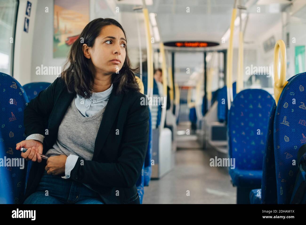 Mujer que usa la pluma de inyección mientras está sentado en el tren Foto de stock