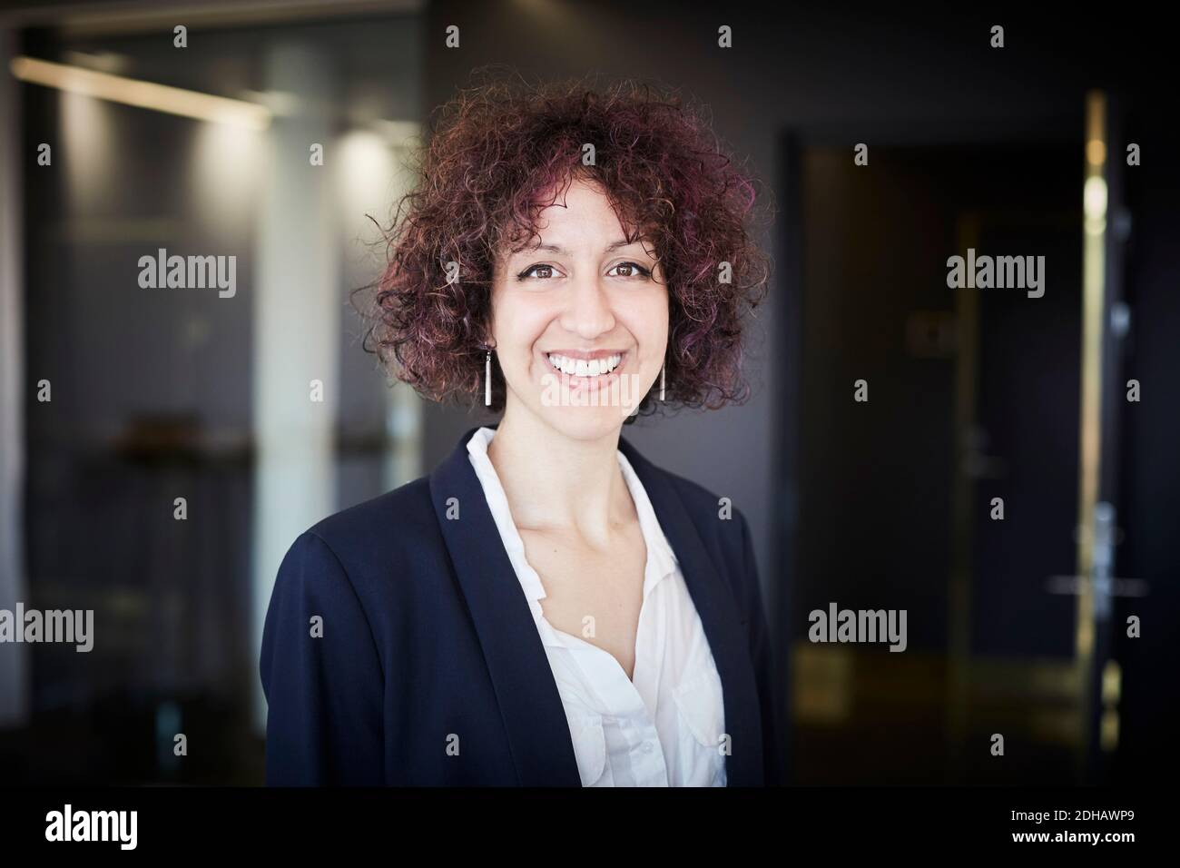 Retrato de sonriente mujer profesional legal con pelo rizado en oficina Foto de stock