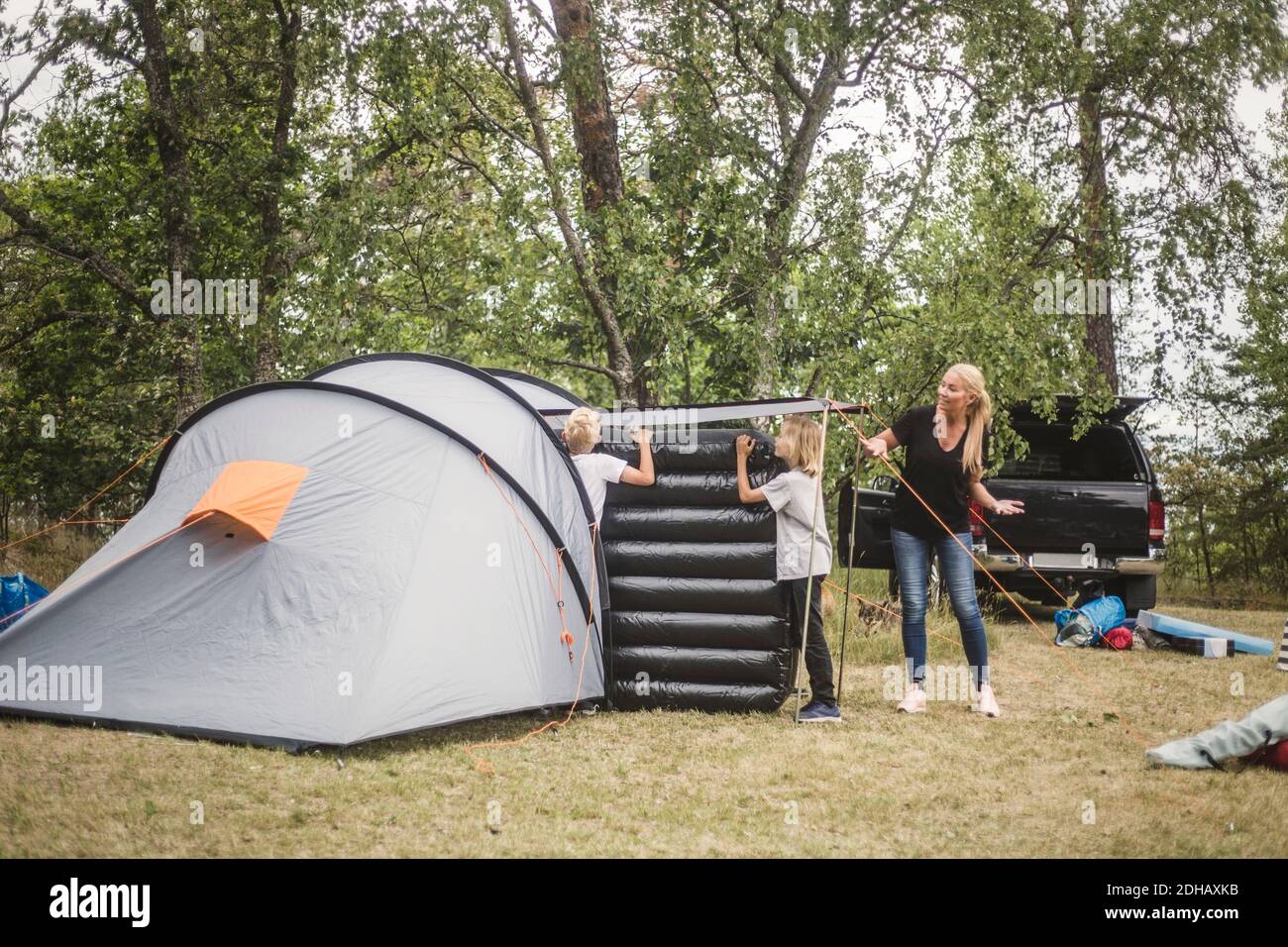 Madre hablando con los niños que llevan el colchón en la tienda de camping sitio Foto de stock