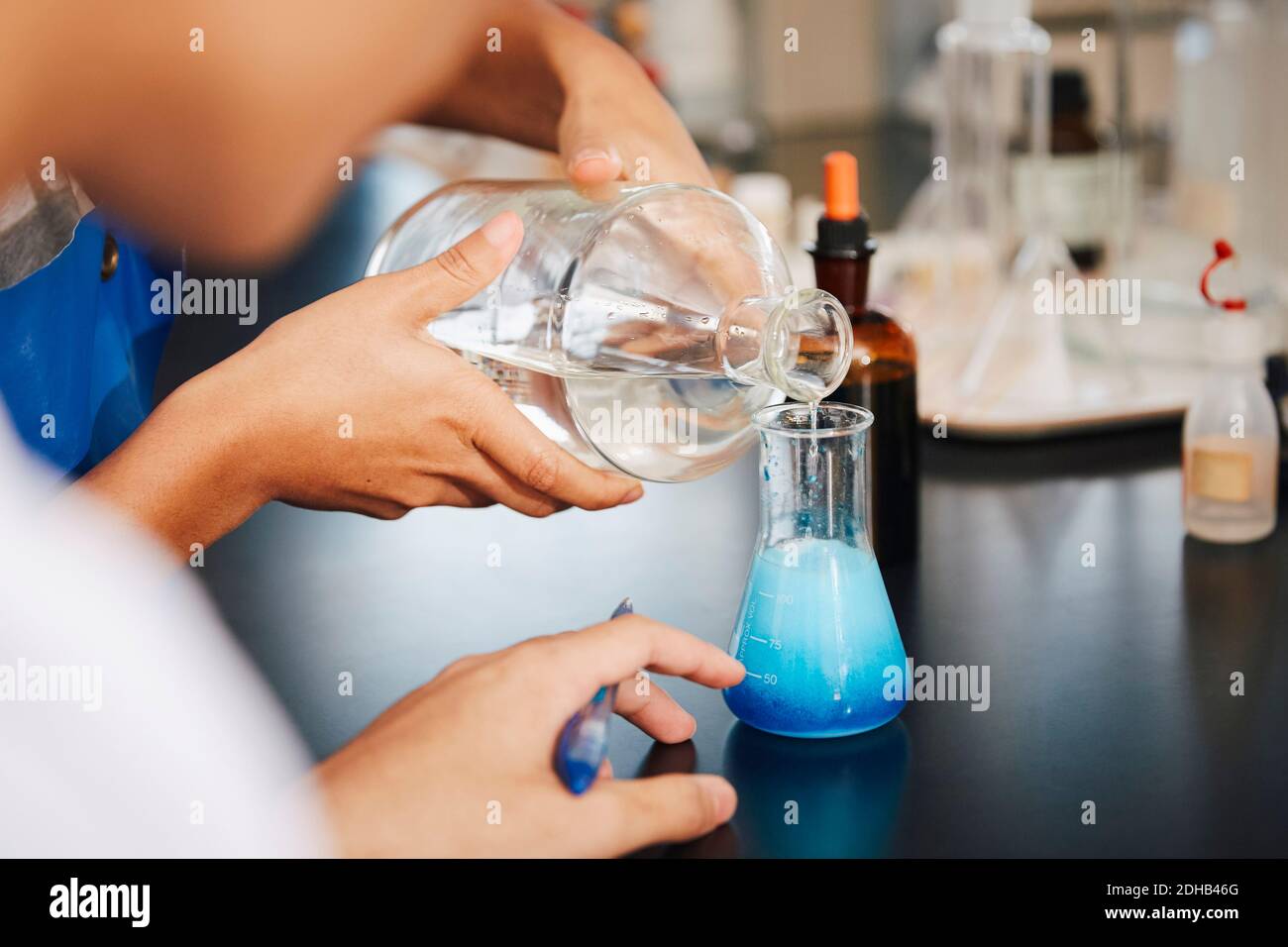 Imagen recortada de estudiantes multiétnicos mezclando soluciones en laboratorio de química en la universidad Foto de stock