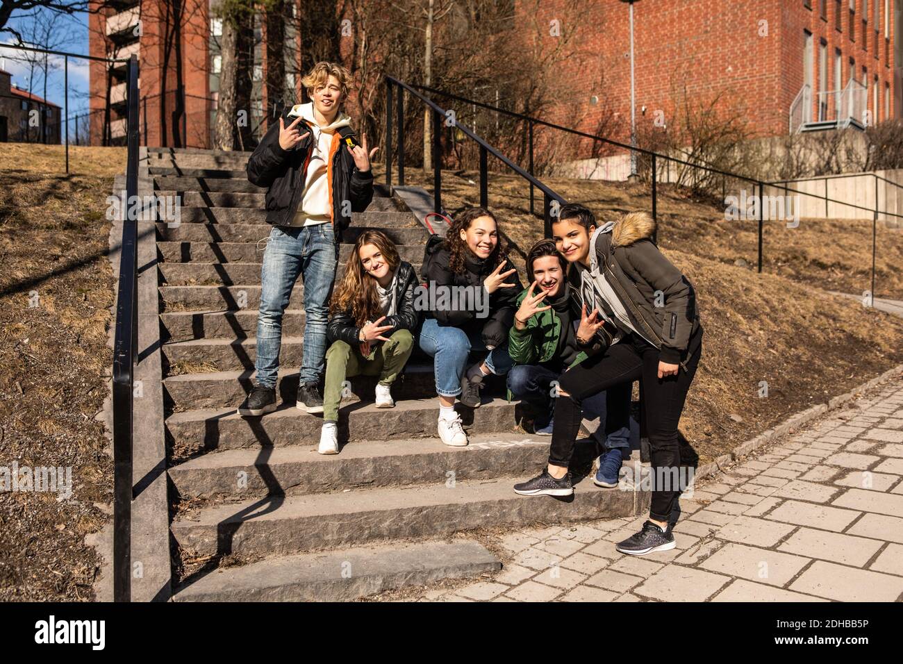 Retrato de alegres amigos adolescentes multiétnicos mostrando señales de mano pasos en la ciudad Foto de stock