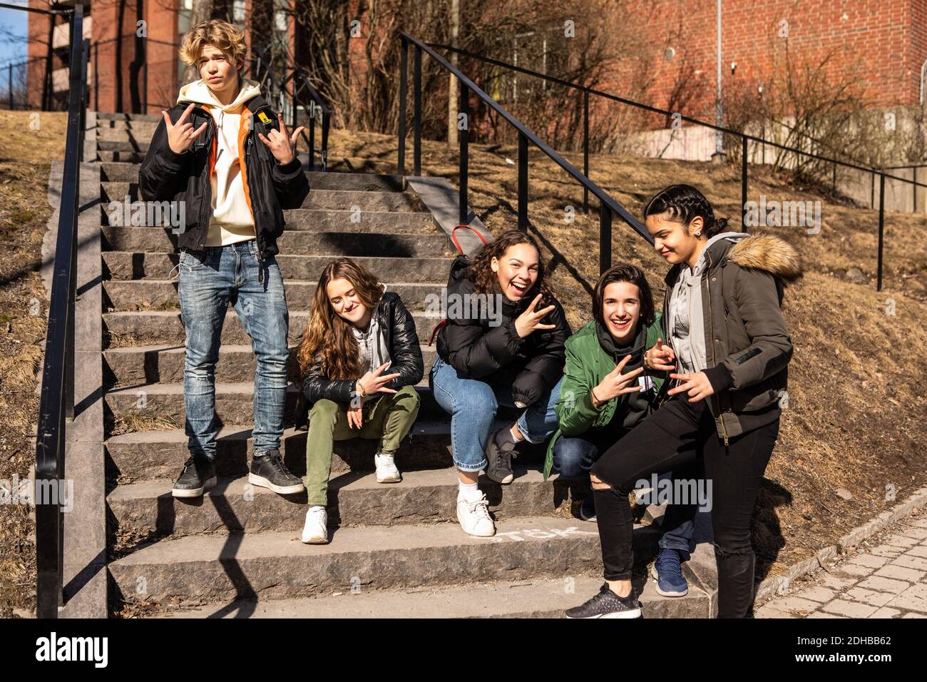 Amigos adolescentes multiétnicos alegres que están en los pasos en la ciudad Foto de stock