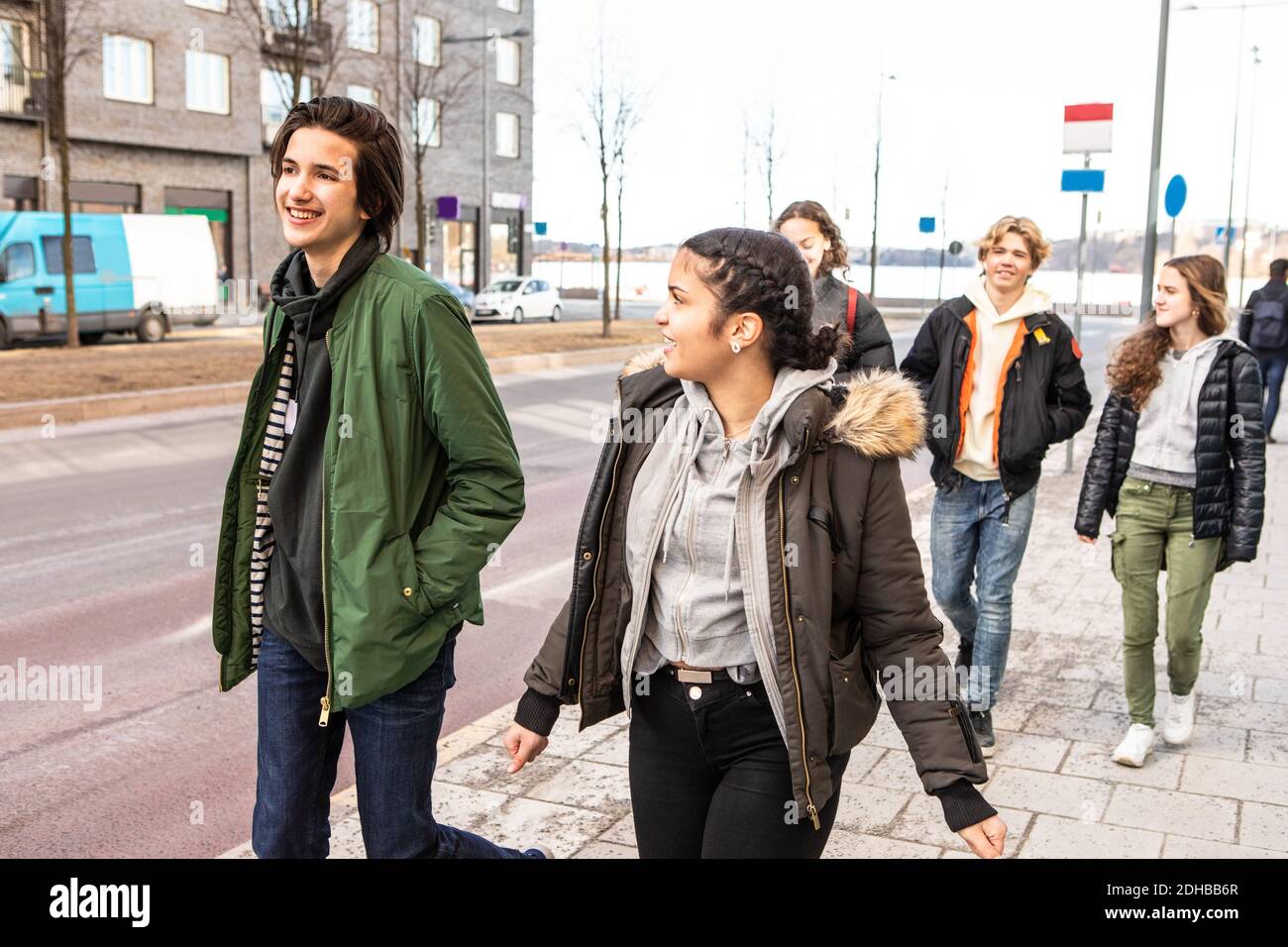 Adolescentes multiétnicos sonriendo con ropa cálida caminando en la acera ciudad Foto de stock