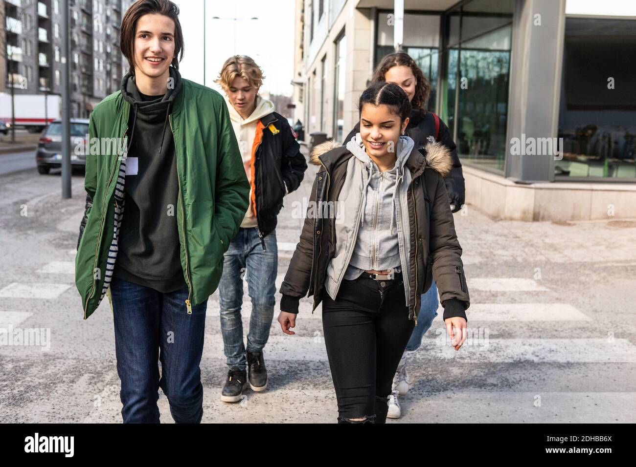 Adolescentes multiétnicos sonriendo cruzando la calle en la ciudad Foto de stock