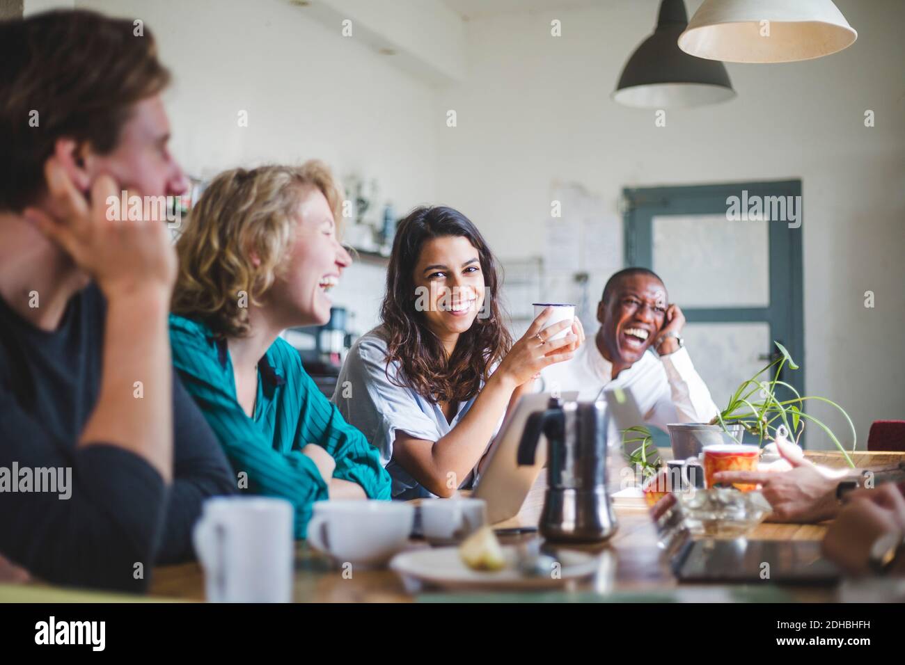 Retrato de alegre joven programador de computadoras sentado con hackers en la mesa en la oficina creativa Foto de stock