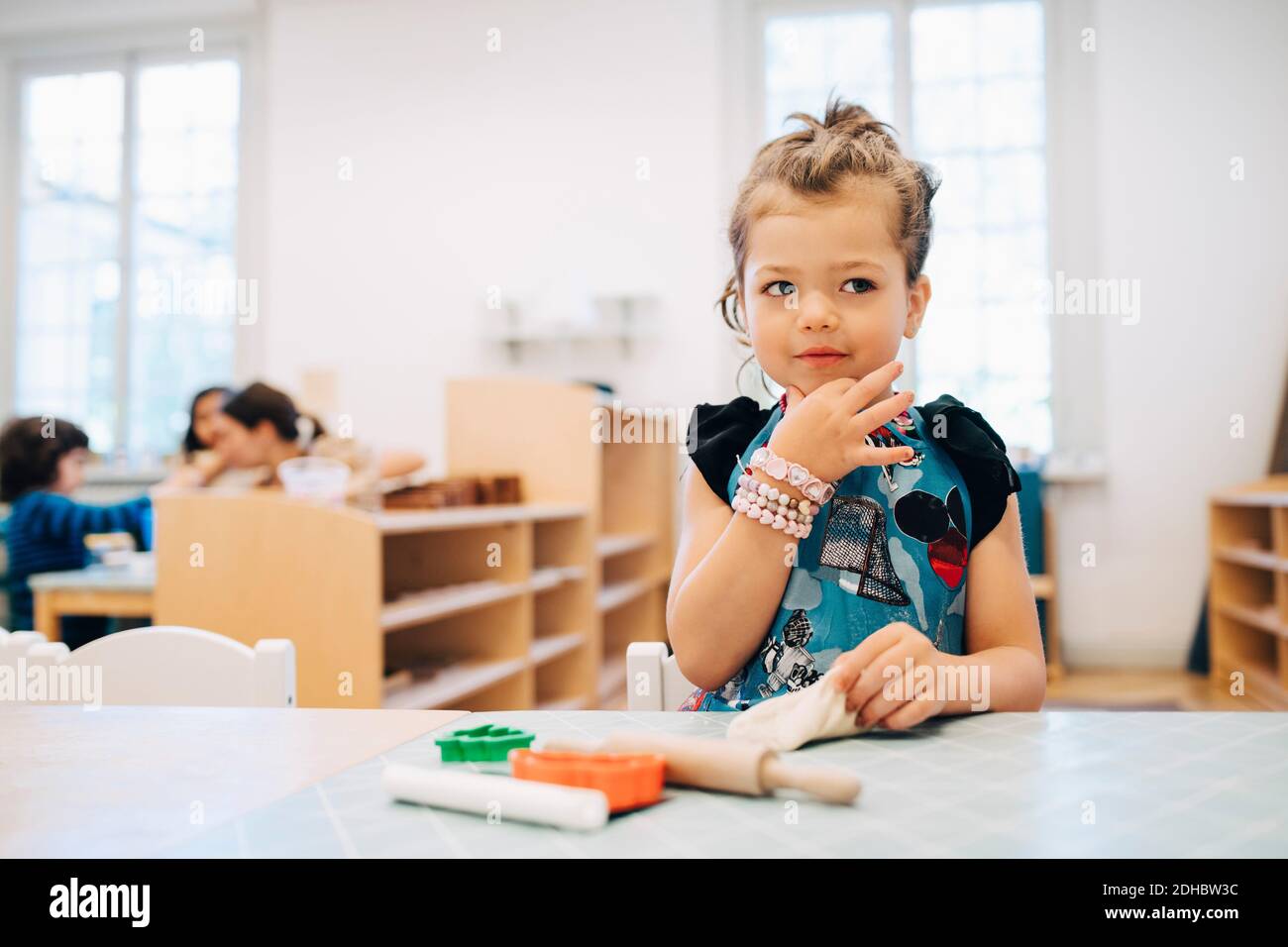 Niña jugando con juguetes en la mesa en el salón de clases de cuidado infantil Foto de stock