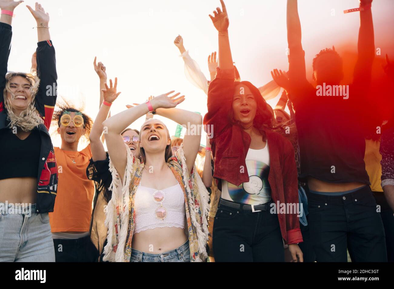 Alegres fans gritando con los brazos levantados contra el cielo durante el verano Foto de stock