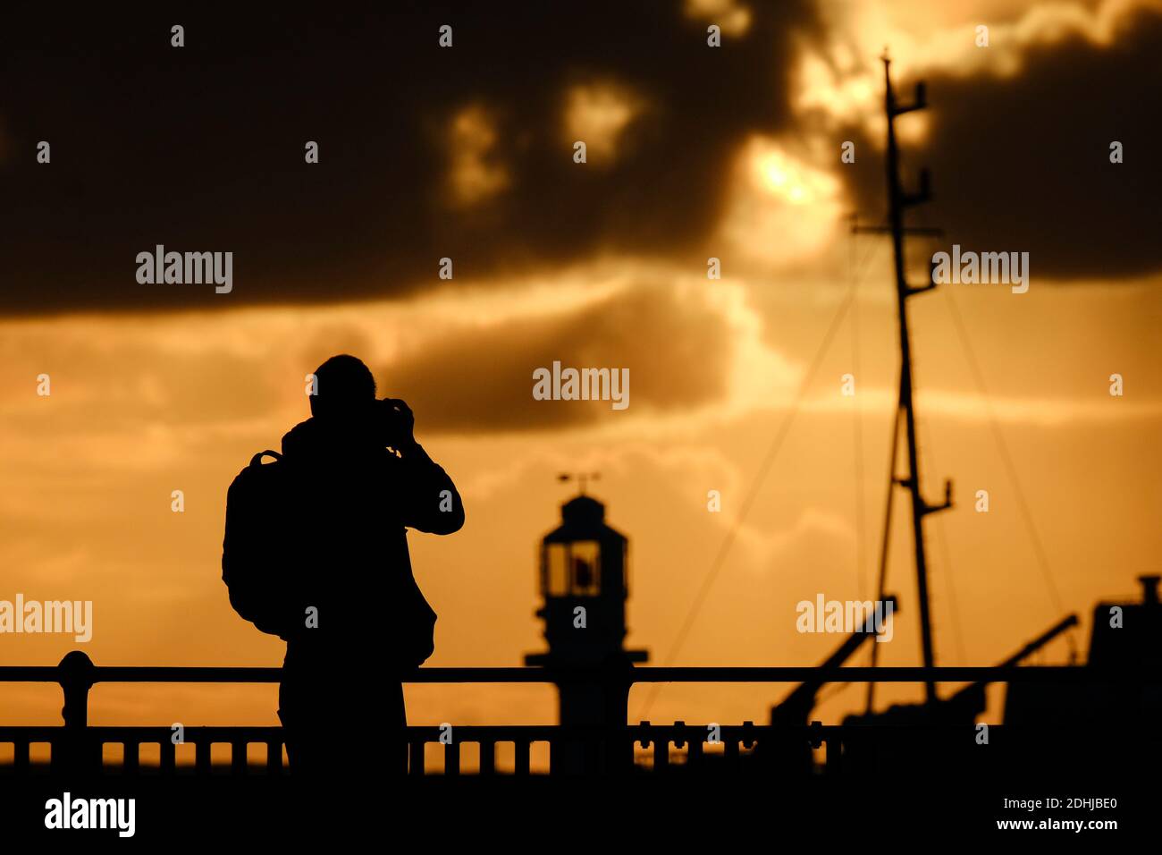 Un fotógrafo captura la calma antes de la tormenta Alex, mientras el sol se levanta detrás del faro del puerto de Penzance el primer día de octubre. Foto de stock