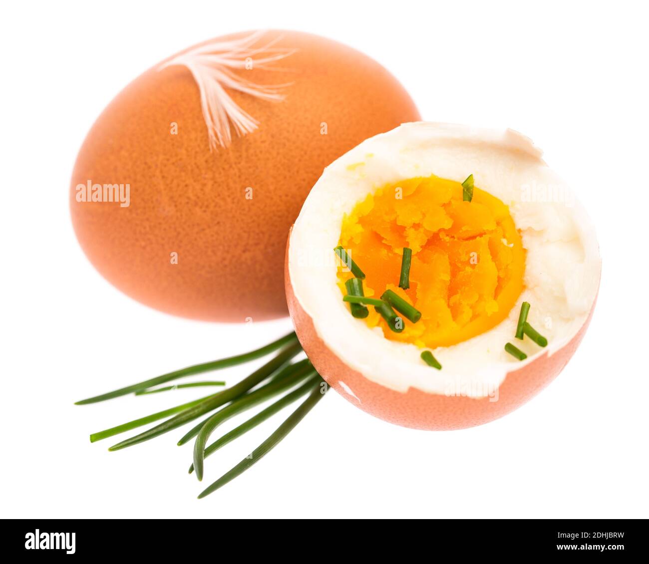 Huevo entero y medio hervido con cebolletas y decoración de plumas sobre un fondo blanco Foto de stock