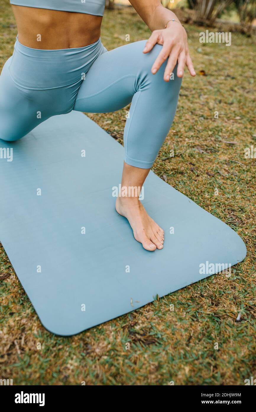 Corta la mujer descalzo delgada irreconocible en leggings azules estirando  el cuerpo En Lunge de la Media Luna en la rodilla pose mientras practica  yoga en el parque Fotografía de stock -