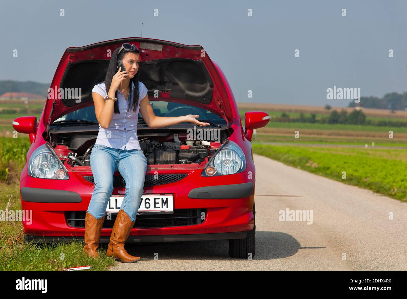 Junge Frau Hat eine Autopanne, Motorschaden, telefoniert mit dem Pannendienst, ADAC, MR: Sí Foto de stock