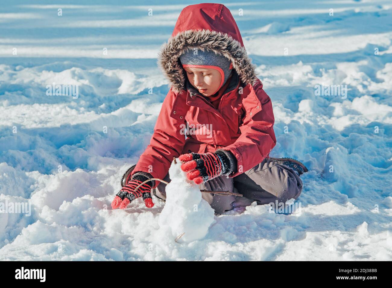 Niña divertida y feliz con ropa de abrigo jugando con nieve en el parque  exterior. Niño niño haciendo muñeco de nieve durante el frío invierno  soleado día brillante. Niños al aire libre