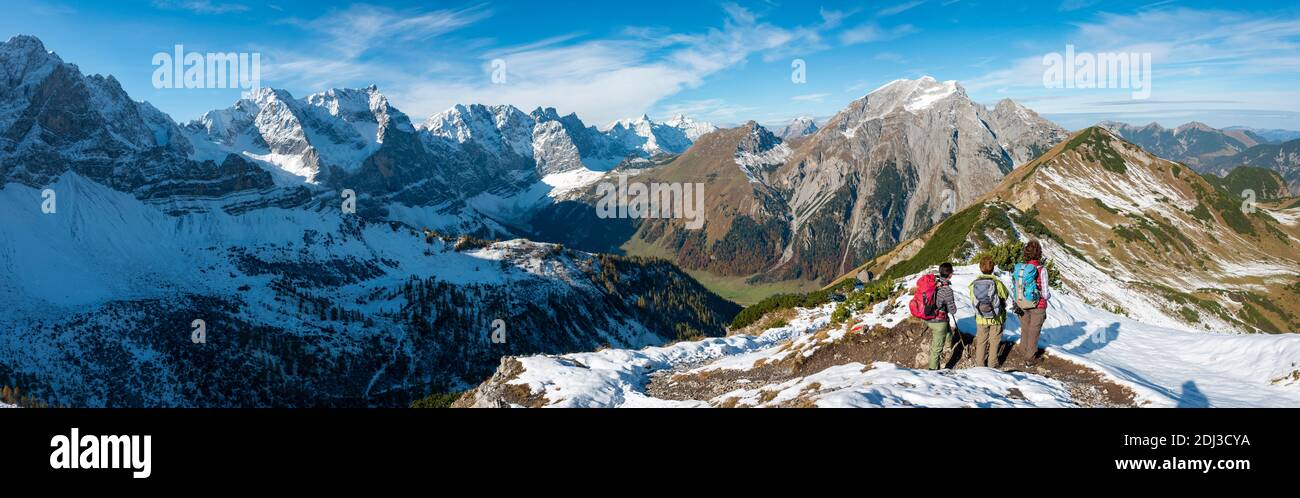 Tres excursionistas en ruta de senderismo con nieve en otoño, caminata hasta la cumbre del Hahnenkampl, vista de los picos nevados Laliderspitze, Dreizinkenspitze Foto de stock