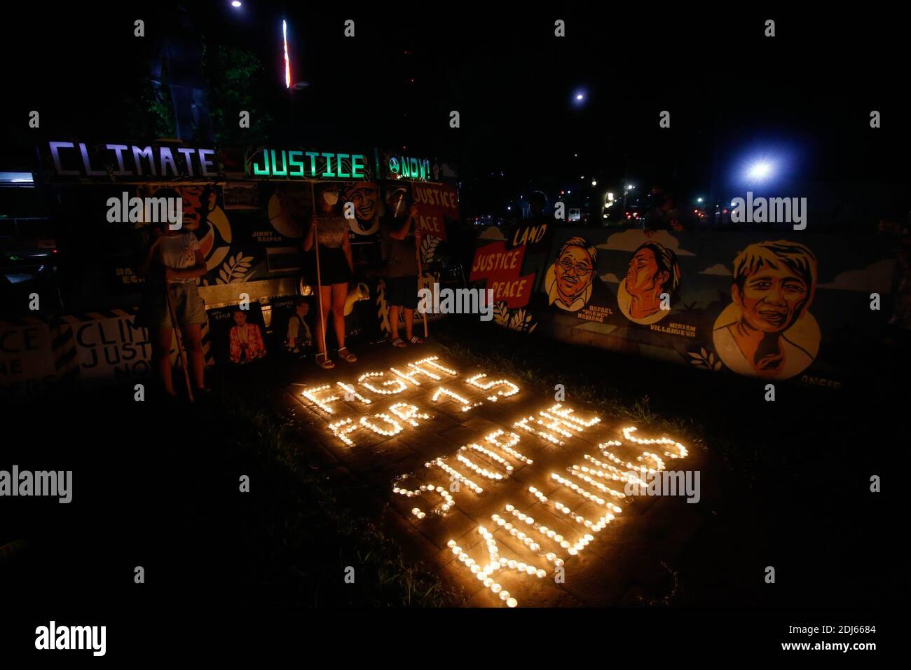 Activistas del clima encendieron velas y llevaron a cabo banderas de iluminación LED el 11 de diciembre de 2020. Esta actividad conmemora el quinto aniversario del Acuerdo de París con un llamado a luchar para 1.5 y a poner fin a la matanza de defensores del medio ambiente. Ciudad de Quezon, Filipinas. Foto de stock