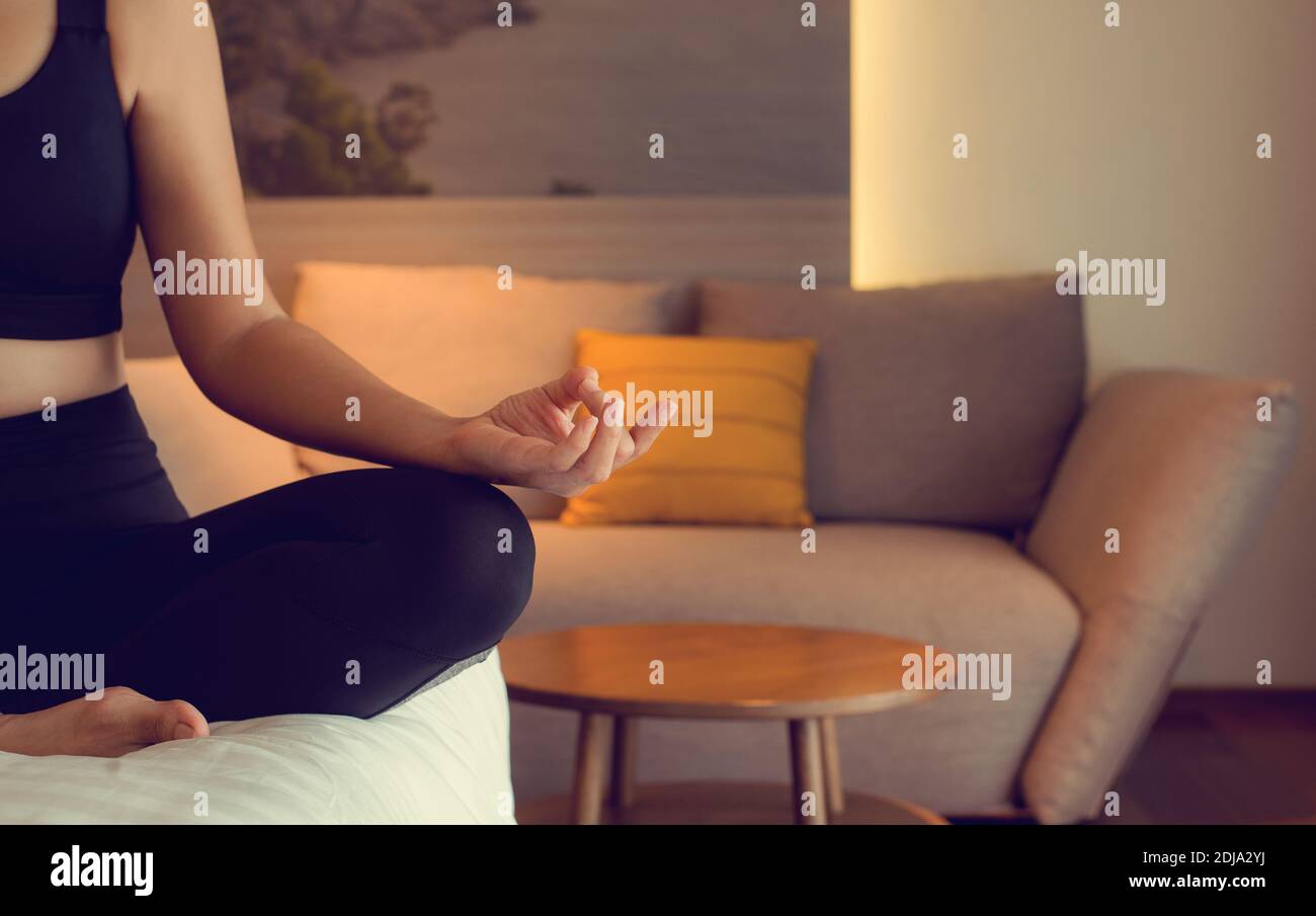 Mujer joven practica yoga loto pose a la meditación en el dormitorio después de despertarse por la mañana. Concepto de cuidado de la salud y ejercicio en el hogar. Foto de stock