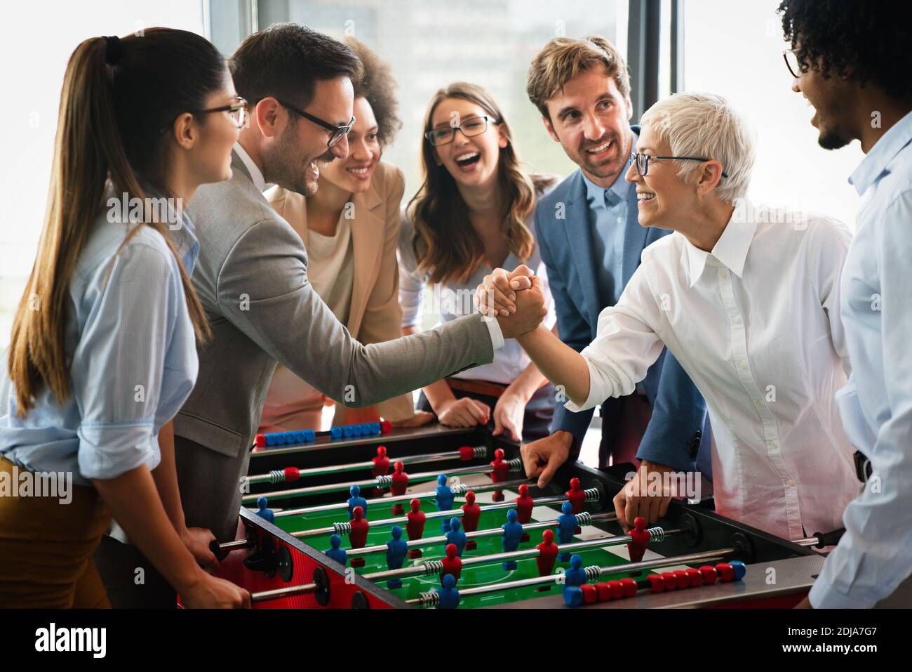 Gente de negocios que se lo pasamos muy bien juntos. Colegas jugando al fútbol de mesa en el cargo. Foto de stock
