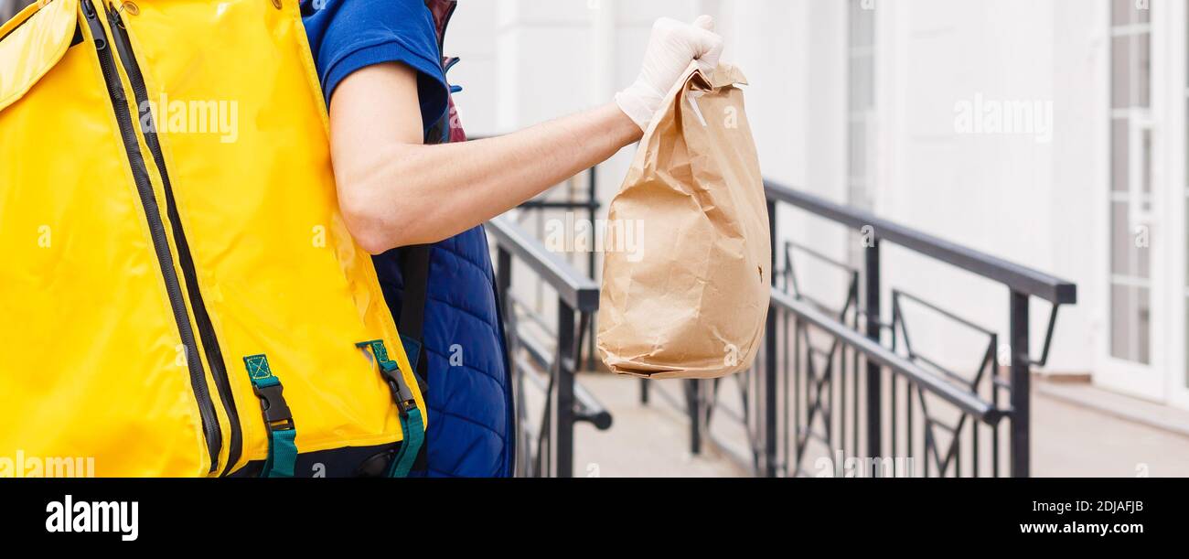 Retrato de un hombre de pie con entrega alegre amarillo Mochila térmica para la entrega de alimentos en la calle al aire libre Foto de stock