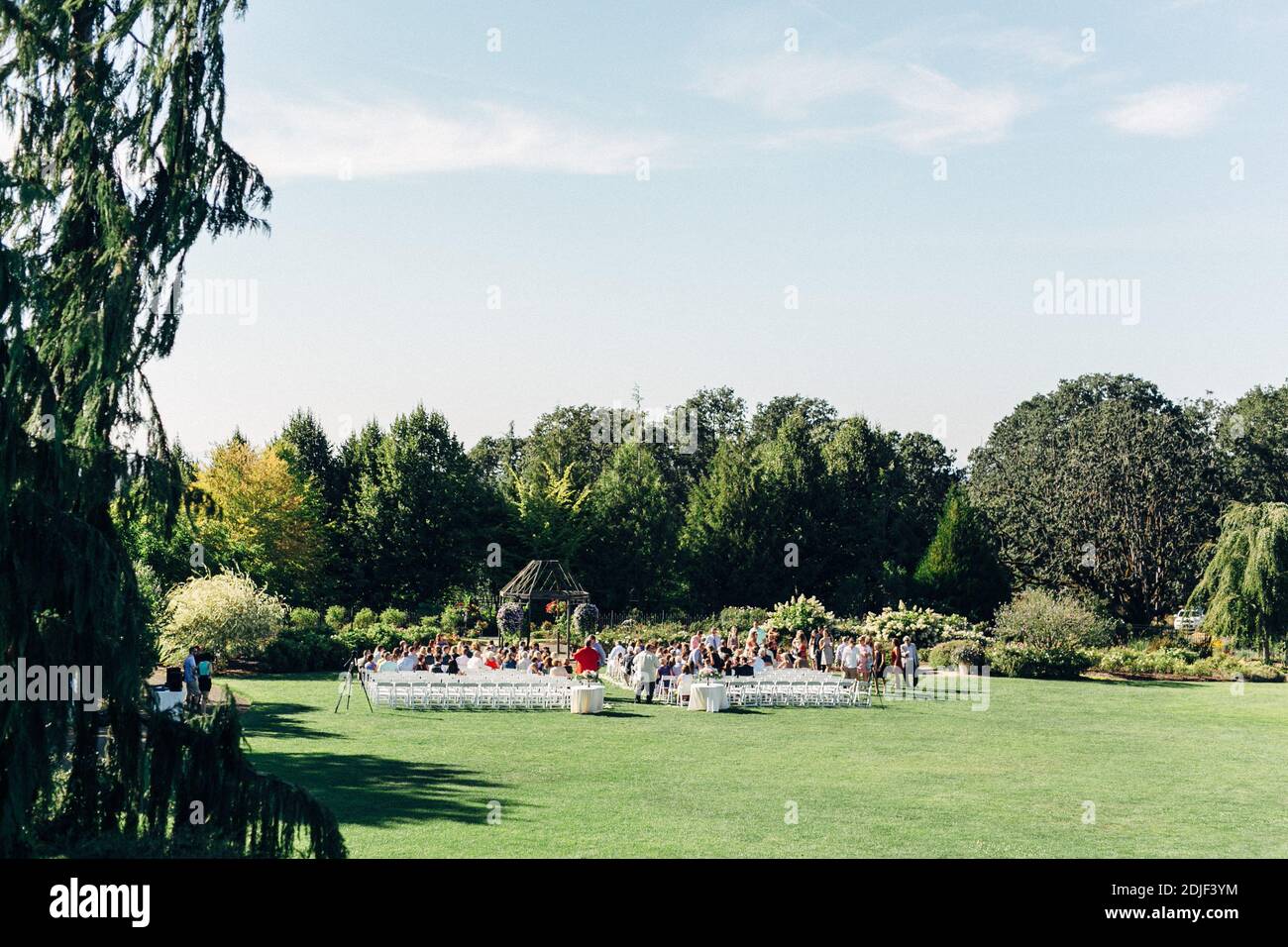 Invitados a la boda sentados en sillas en el parque púbico contra el cielo Foto de stock
