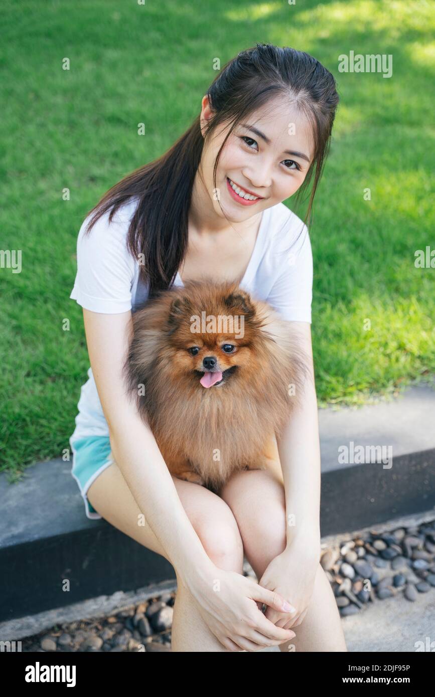 Retrato de una joven sentada con un perro en el parque Foto de stock
