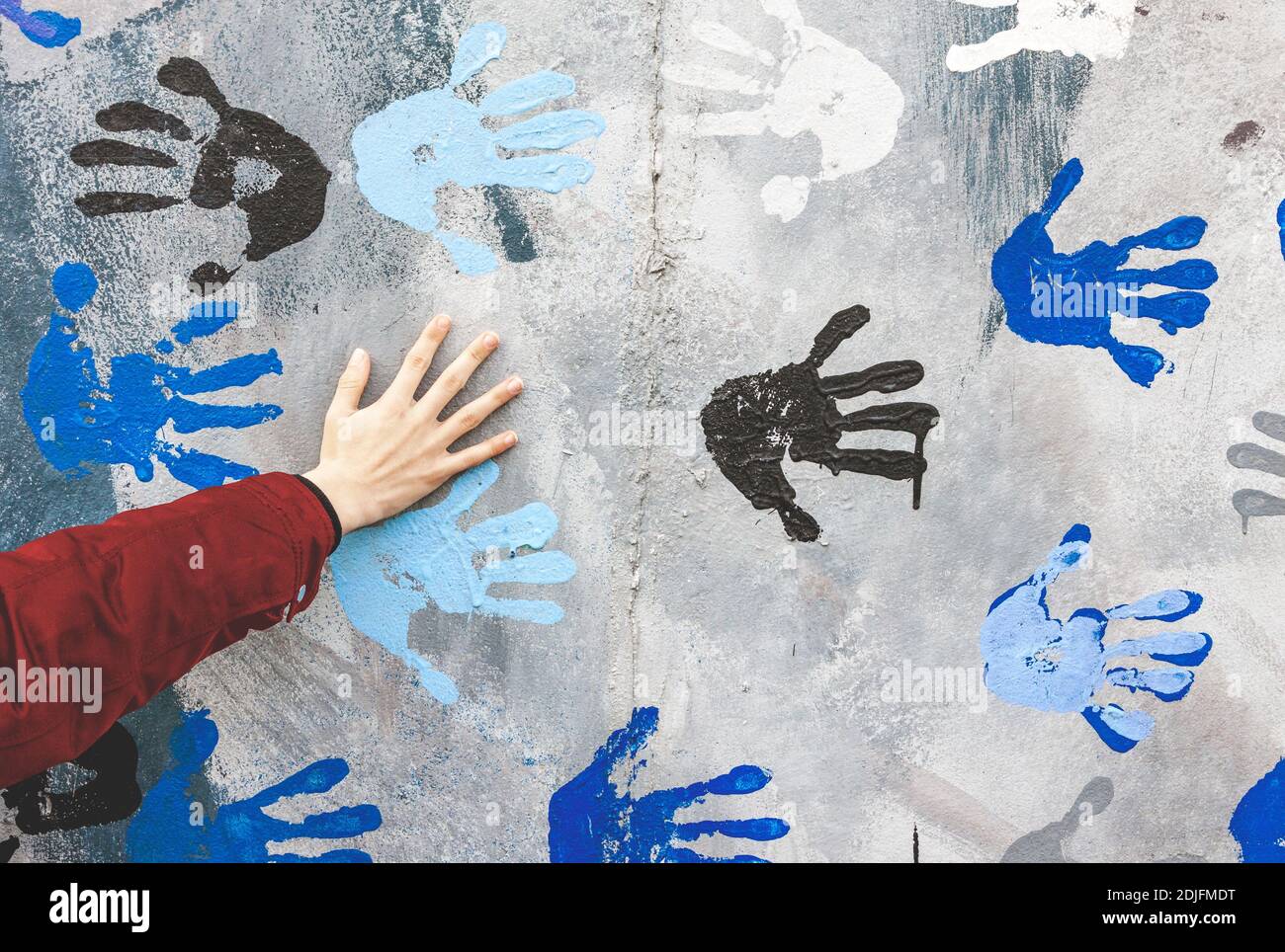 Palma humana en muro de hormigón pintado con colores aleatorios manos impresas Foto de stock