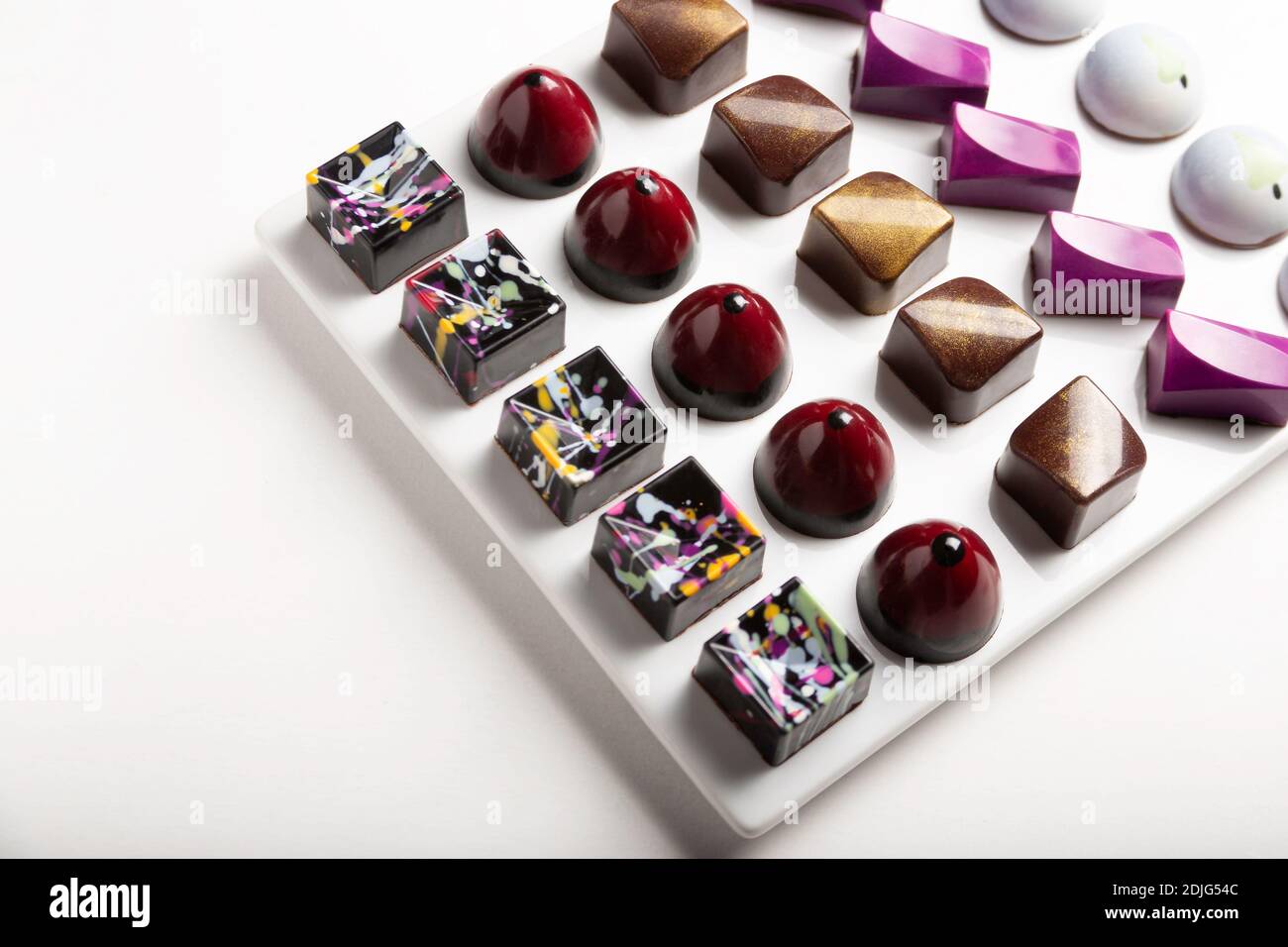 variedad de lujosos bonbones de chocolate hechos a mano con ganache sobre fondo blanco. Exclusivo bonbon artesanal Foto de stock