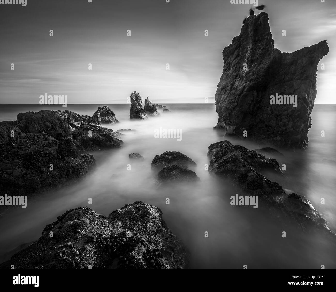 Larga exposición de el Matador State Beach puesta de sol con la roca en el primer plano y las olas rompiendo, Malibu, California Foto de stock