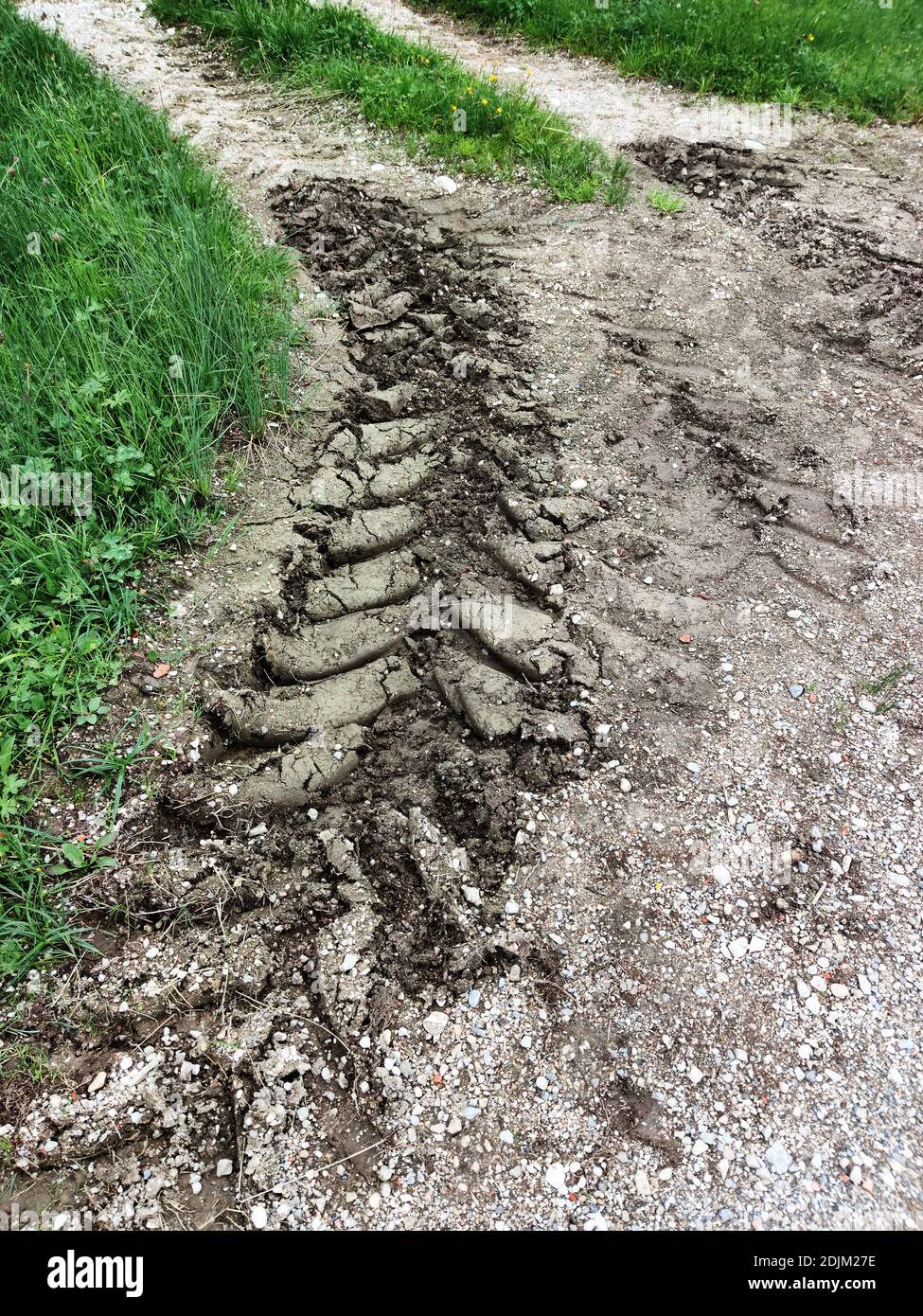 deep tire track from tractor on gravel road after rain Foto de stock