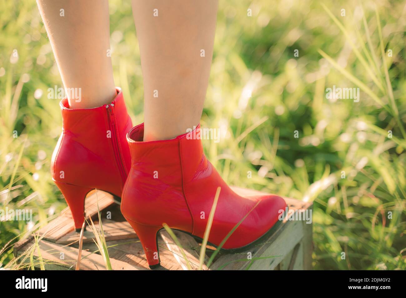 Sección baja de la mujer que lleva botas rojas de pie en la caja de madera  Fotografía de stock - Alamy