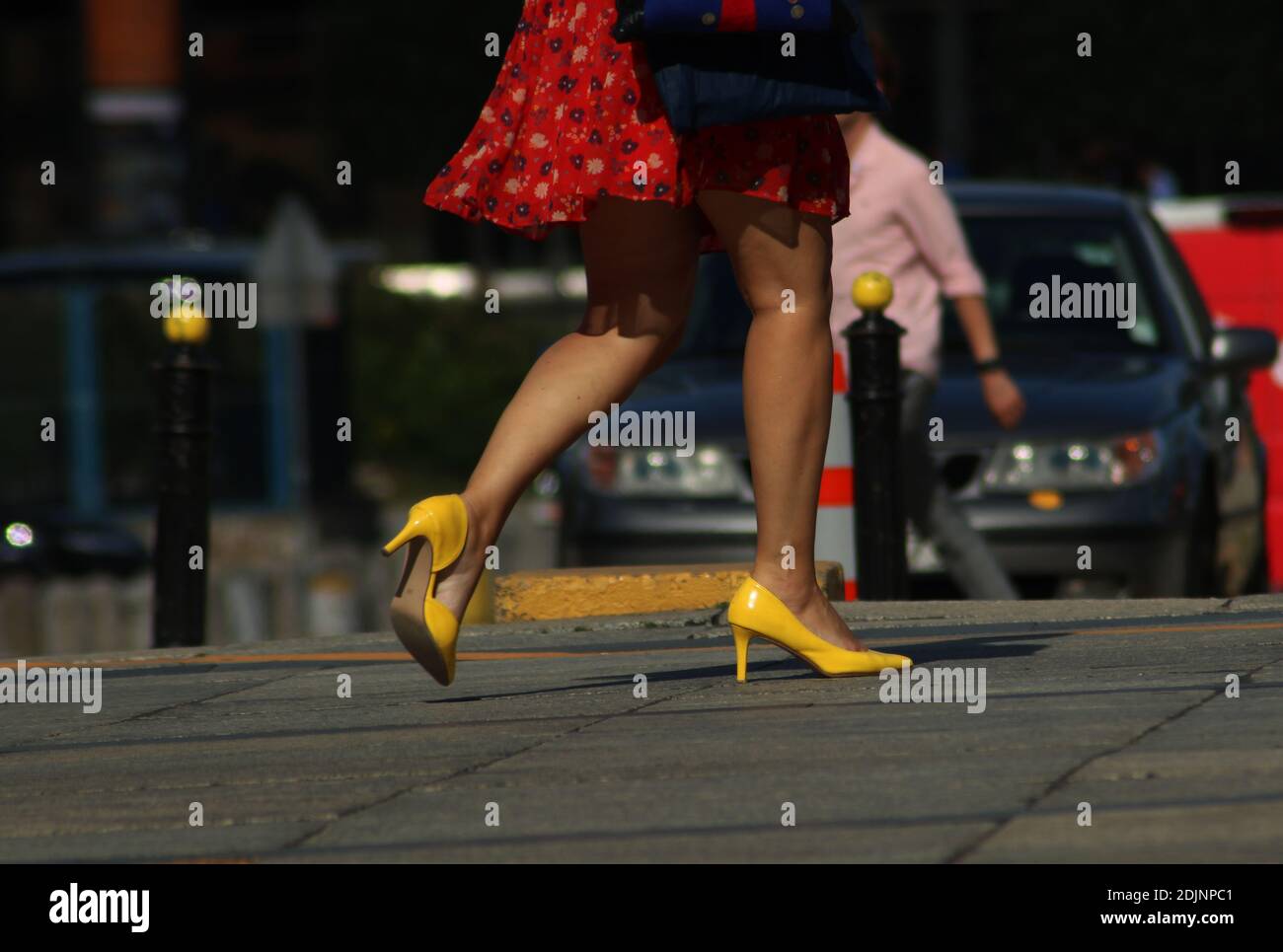 Sección baja de la mujer usando tacones altos amarillos mientras caminaba  en la calle Fotografía de stock - Alamy