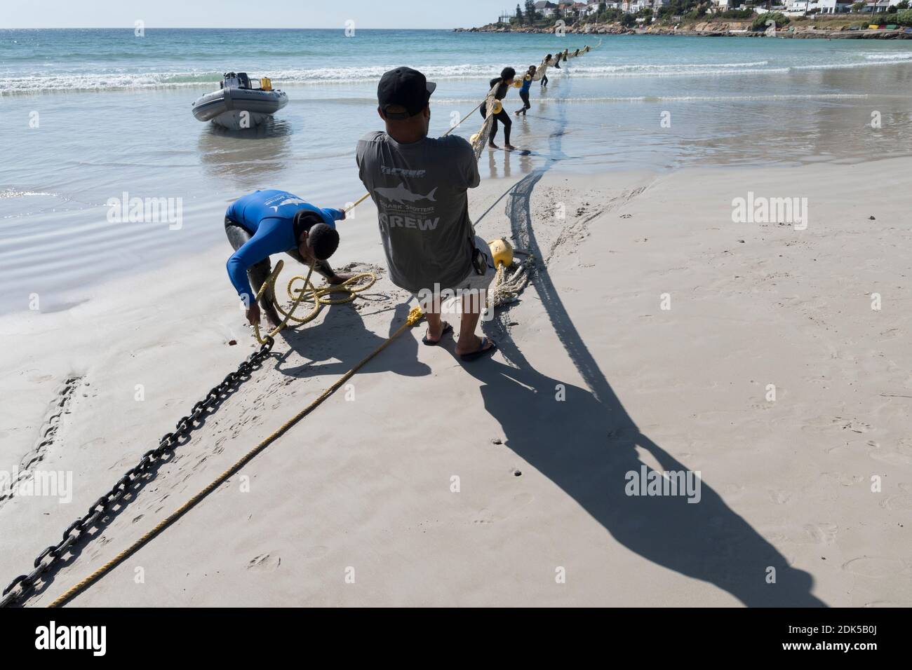 Una tripulación de Shark Spotters despliega una barrera neta de exclusión de tiburones en Fish Hoek Beach, False Bay, Ciudad del Cabo, Sudáfrica. Protección contra la badera. Turismo. Foto de stock