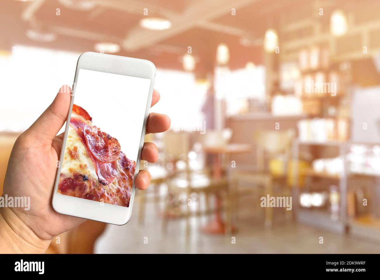 Manos recortadas sosteniendo el teléfono móvil con foto de comida en la pantalla del Café Foto de stock