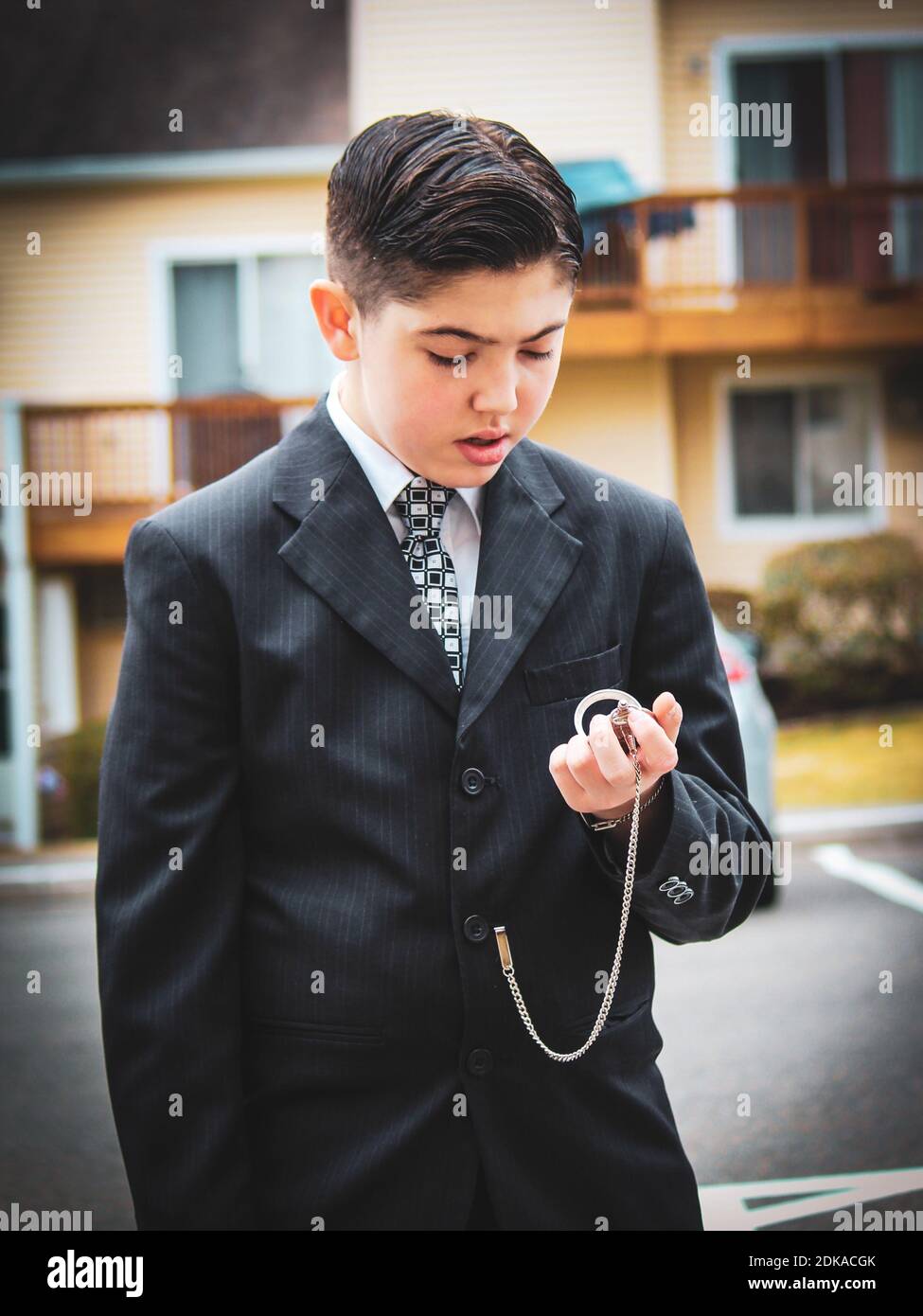 Niño en traje sosteniendo reloj de bolsillo mientras está de pie en la  ciudad Fotografía de stock - Alamy