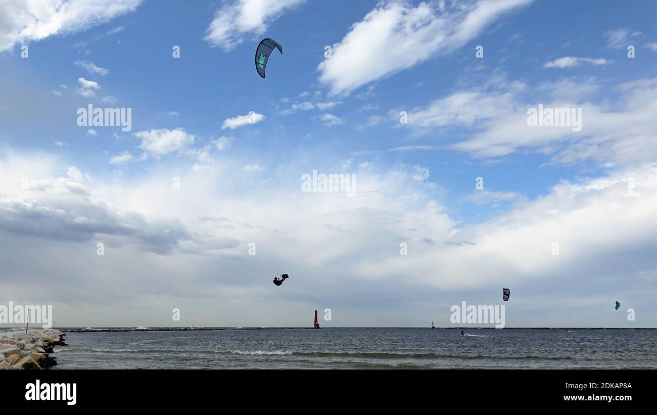Un kite-boarder windsurf en un día poco nublado con un faro en el fondo Foto de stock