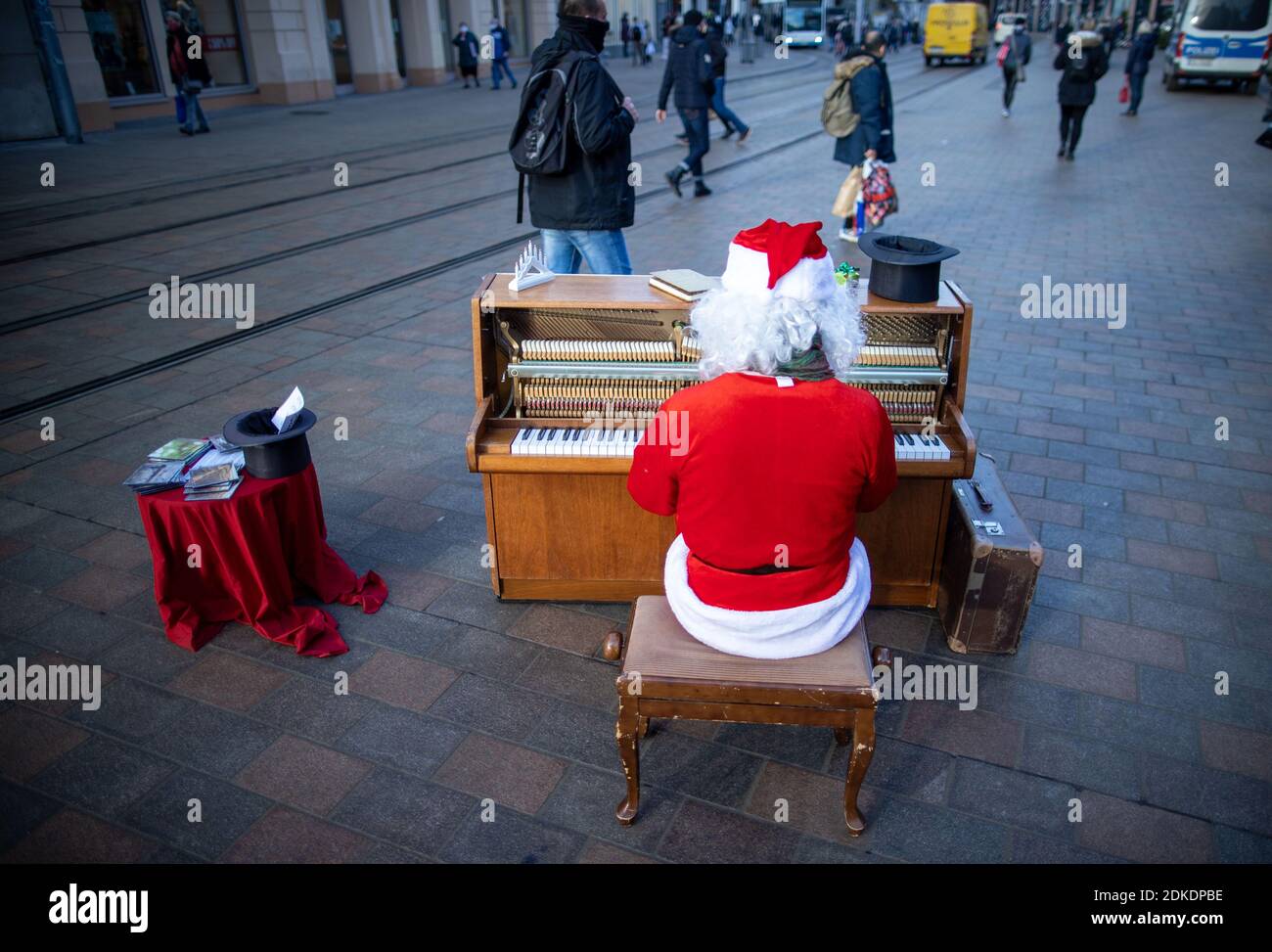 Schwerin, Alemania. 15 de diciembre de 2020. Un músico callejero vestido  como Santa Claus toca su piano móvil en el centro de la ciudad. Un día  antes del cierre de grandes partes