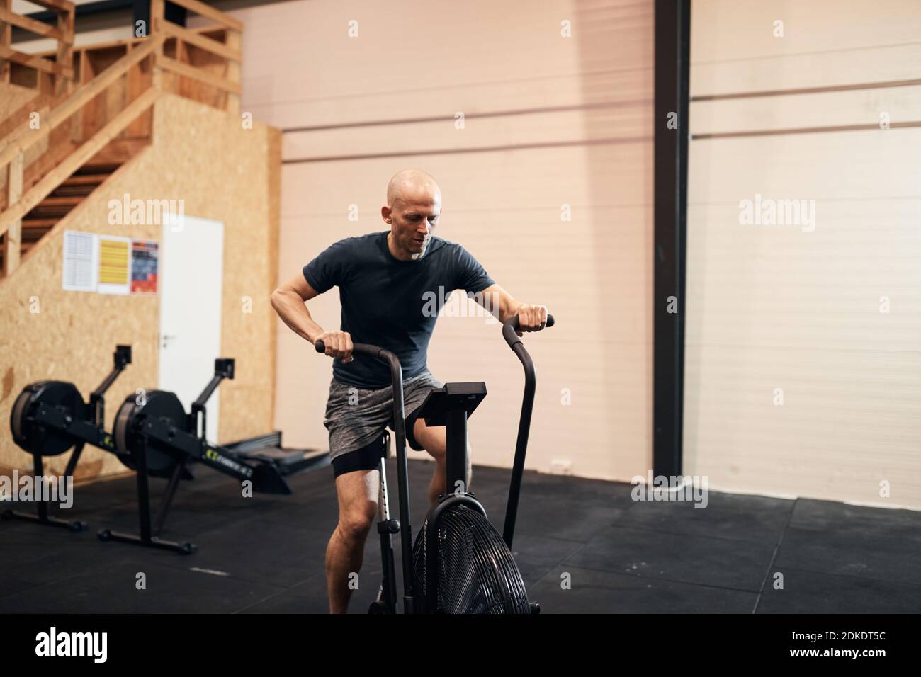 El hombre en forma de ropa deportiva a caballo en una bicicleta estática  durante una sesión de ejercicio en el gimnasio Fotografía de stock - Alamy