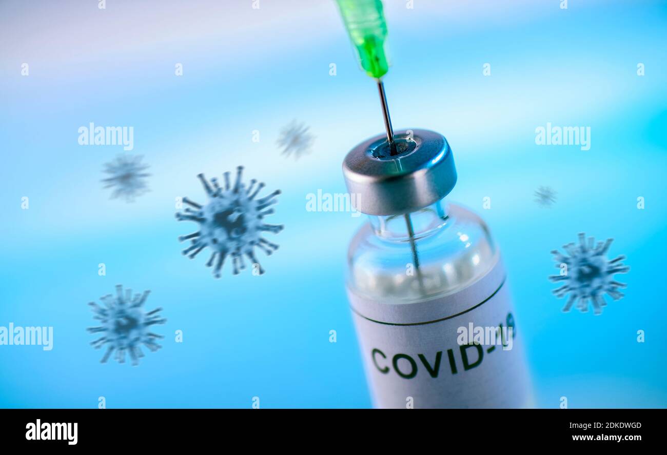 Material de inyección etiquetado Covid-19 y la aguja de una jeringa sobre un fondo azul con virus Foto de stock