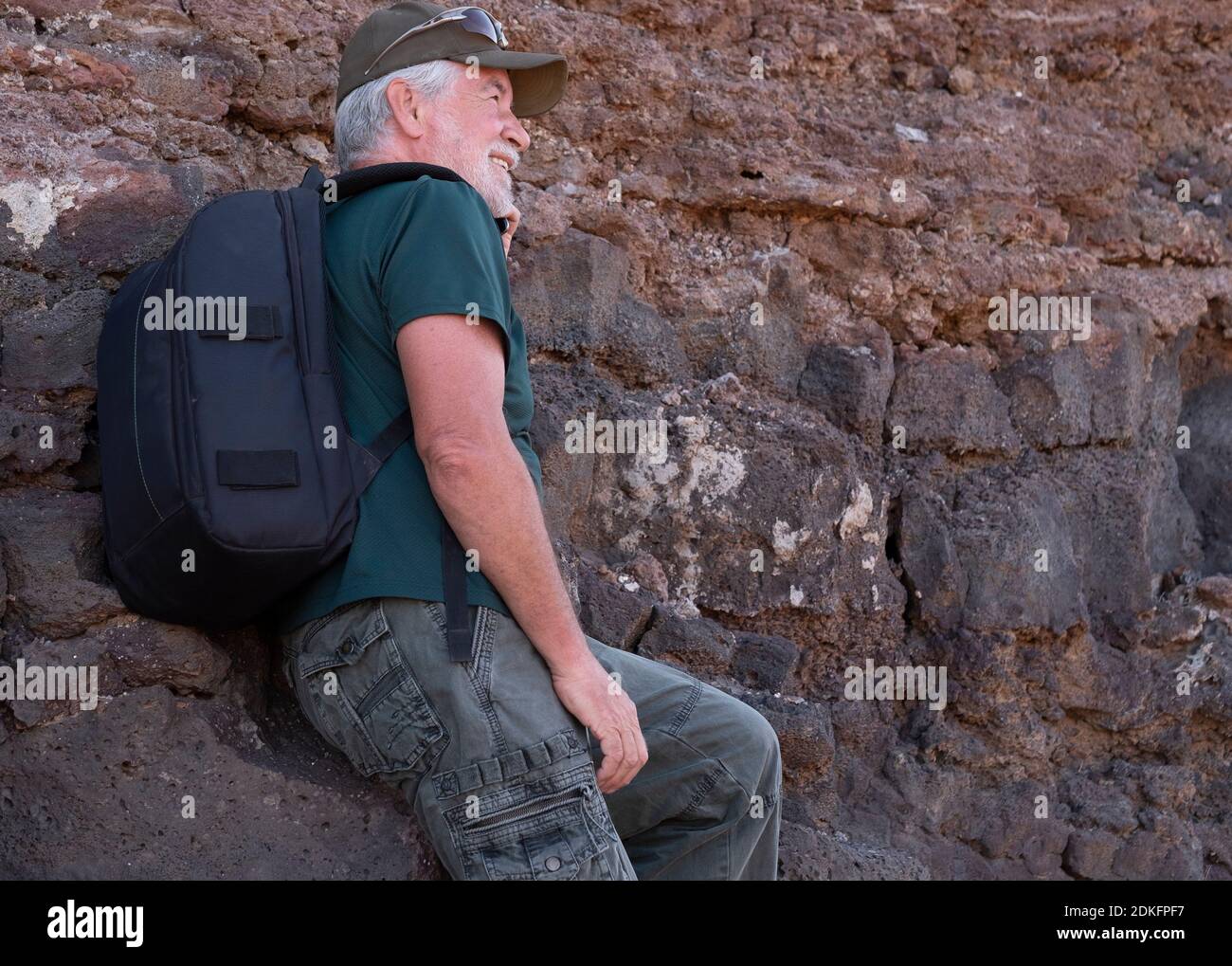 Vista lateral de un hombre mayor con mochila caminando en excursión al aire  libre y descansando en las rocas. Excursión en un sitio de montaña  Fotografía de stock - Alamy