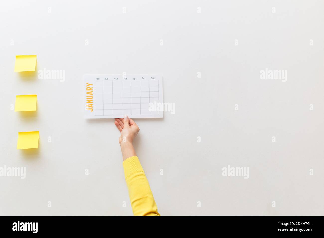 La mano de una mujer cuelga un nuevo calendario para enero.Planificación de nuevo año, meta, acción, estrategia, decisión, éxito de negocio.concepto mínimo.espacio de copia Foto de stock