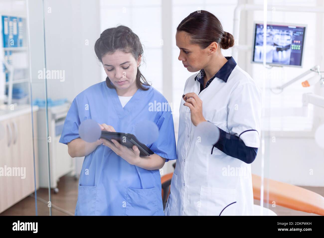 Dentista en el consultorio de estomatología explicando el diagnóstico de dientes a la enfermera de dentición. Especialista en ortodoncia y clínica dental auxiliar hablando sobre el tratamiento de los dientes. Foto de stock