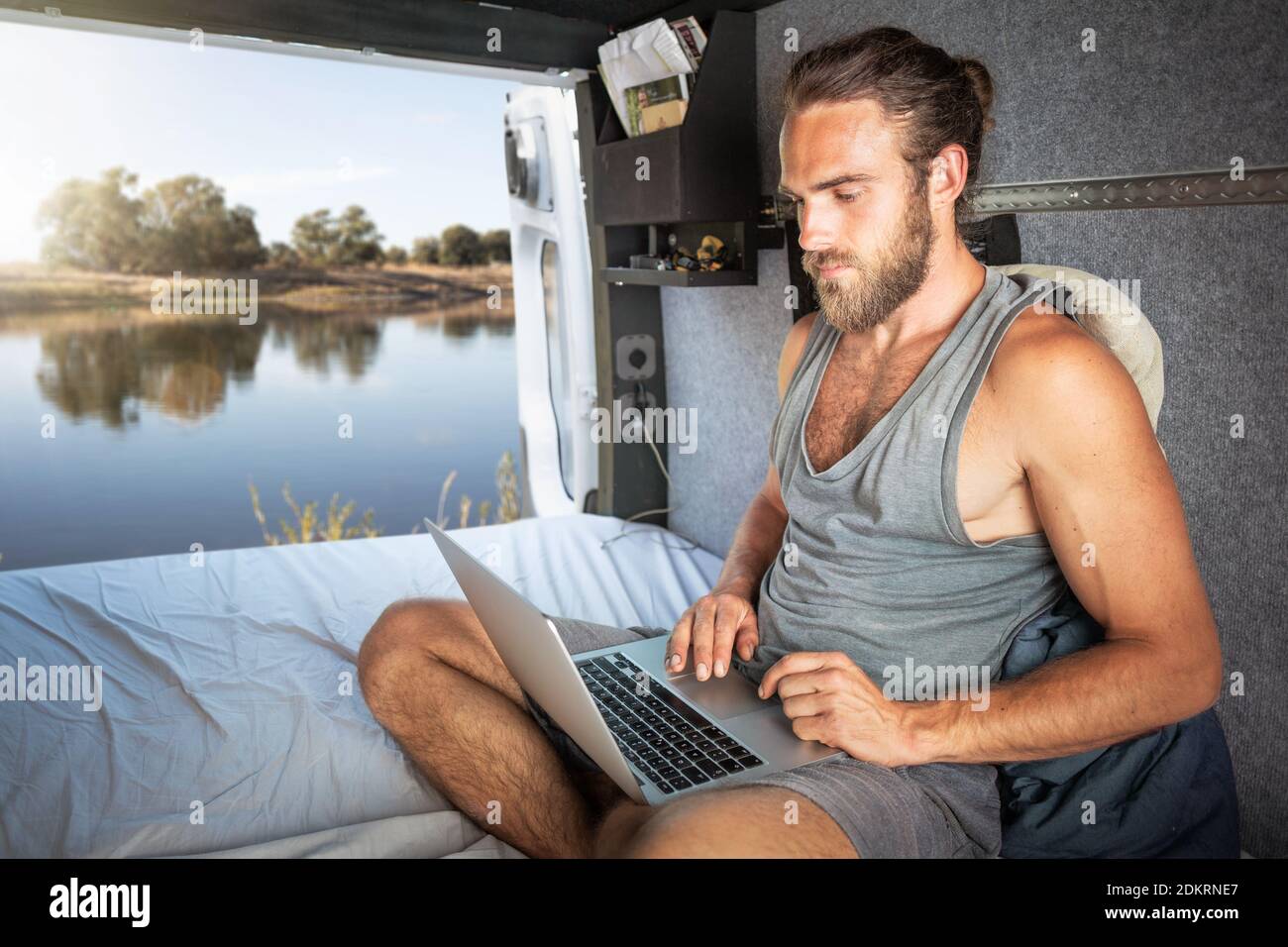 Hombre usando un ordenador portátil dentro de su caravana Foto de stock