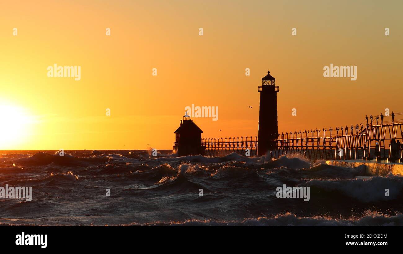 Grand Haven South Pier Lighthouse al atardecer en el lago Michigan, en un día ventoso Foto de stock